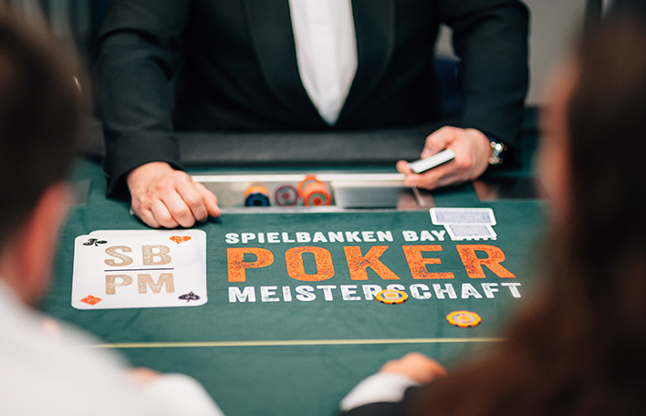 Szene am Pokertisch: Blick über die Schultern zweier Personen auf die Hände des Dealers