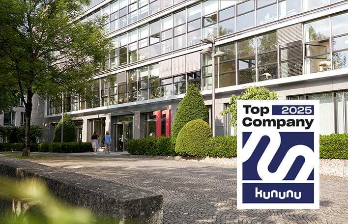 Eingangsbereich der Münchner Unternehmenszentrale, im Bild integriert das Logo der Auszeichnung "Top Company 2025" durch kununu.com