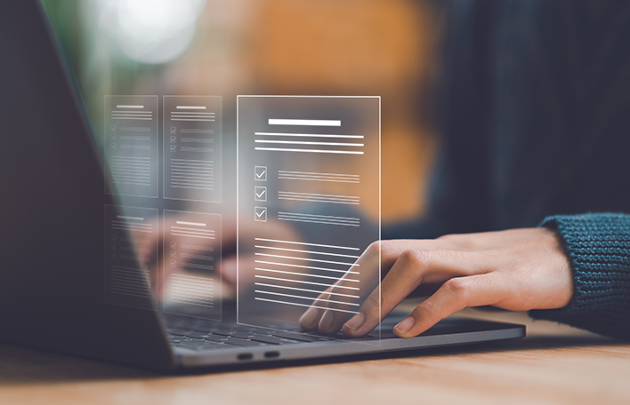 Visualisierung Hände an einem Laptop und Textdokumente. AdobeStock/chaylek