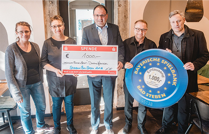 Vertreter vom BAM. Bistro am Markt und dem Evang. Diakonieverein Wunsiedel e.V. freuen sich gemeinsam mit dem Finanz- und Heimatstaatssekretär und dem Spielbankdirektor über die Spende.